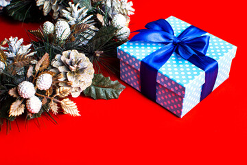 Beautiful classic blue gift box with ribbon, fir branches and golden cones.