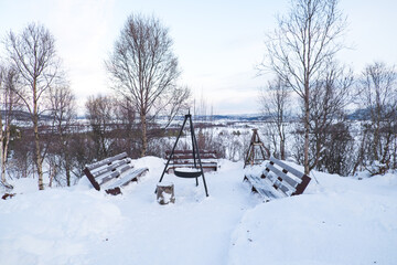 Several park benches are covered in snow during a cold winter day in Tromso, Norway.