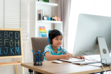 Asian boy student video conference e-learning with teacher and classmates on computer in living...