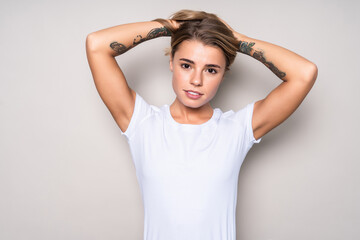 Fototapeta premium Close-up portrait of cute young woman with hands on head isolated on white background