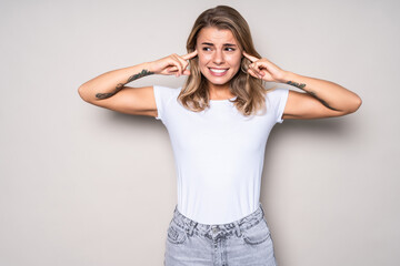 Sad young woman covering her ears isolated on white background