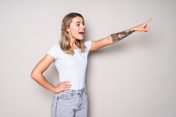 Excited woman point finger showing something to side empty copy space isolated over white background