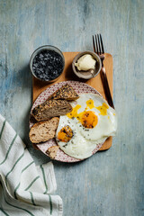 plate of fried eggs with seed bread, black salt and butter, breackfast toast.