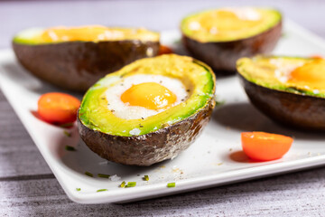 Aguacate con huevo al horno en un primer plano y con tomates cherrys