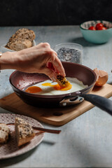 hand dips bread in the fried egg, in the pan