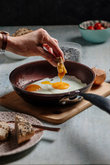hand dips bread in the fried egg, in the pan
