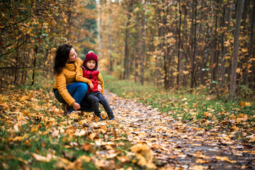 Young mother with her little baby boy having fun in the autumn park
