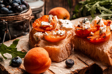 Healthy summer appetizer or snack Toast with soft dor blue cheese, fresh juicy peach, blueberry and...