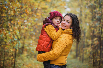 Young mother with her little baby boy having fun in the autumn park