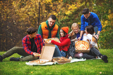 Friends young funny beautiful enjoy pizza and socializing on a picnic in nature together