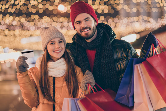 Black friday. Photo of two people students friends hold shopping bags credit card under x-mas christmas outdoors evening lights