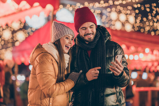 Photo of two people students friends browse social media on smartphone point finger x-mas christmas outdoors event