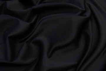 Smooth elegant black silk satin fabric texture  as abstract background. Luxurious pattern for design.