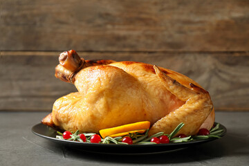 Delicious cooked turkey served with rosemary, oranges and cranberries on grey table. Thanksgiving Day celebration