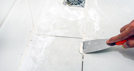 Grouting tile seams with a stainless steel trowel.Grouting ceramic tiles.