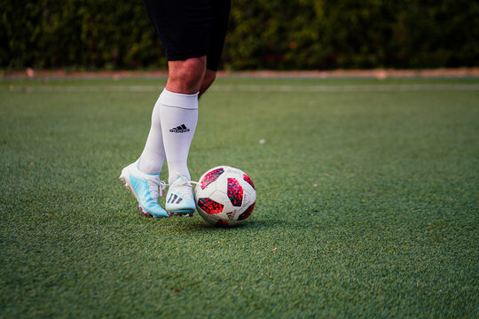 Bangkok/Thailand - December 2019 : A football player is practice to dribbling the ball on local turf ground. He wears Adidas "X 19" shoe model which is designed for speed player. Selective focus photo