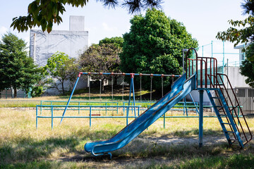 Fototapeta premium 青いブランコと滑り台のある公園