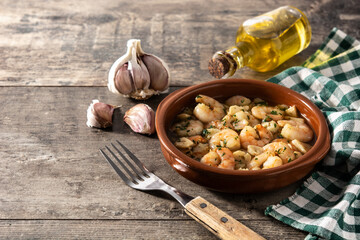 Garlic prawns in crockpot on wooden table.Copy space	