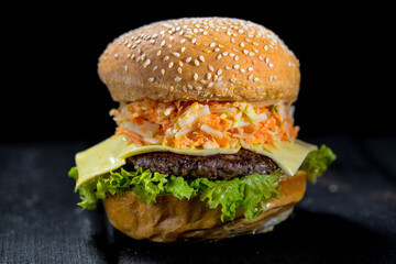 big burger with salad and cheese with big cutlet black background
