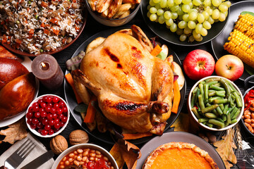 Traditional Thanksgiving day feast with delicious cooked turkey and other seasonal dishes served on black wooden table, flat lay