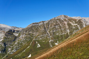 sunny high-mountain slopes with alpine meadows and strips of geological layers - spurs of Mount...