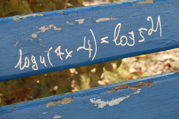 Mathematical equation written on a wooden park bench