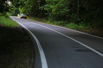 Fototapeta na wymiar winding dangerous forest asphalt road with markings