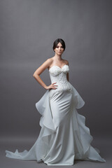 Fototapeta premium Beautiful bride in wedding dress posing on grey background