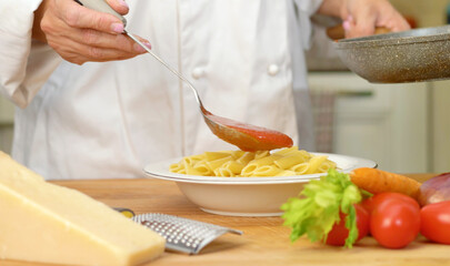 mixing penne and tomatoes sauce in the dish