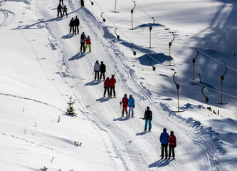 skiers taking drag lift up the mountain, ski snowy landscape