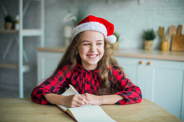 Cheerful girl in santa claus hat at home smiling