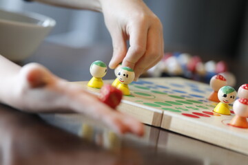 Board game with child's hand, toy figure and red die.