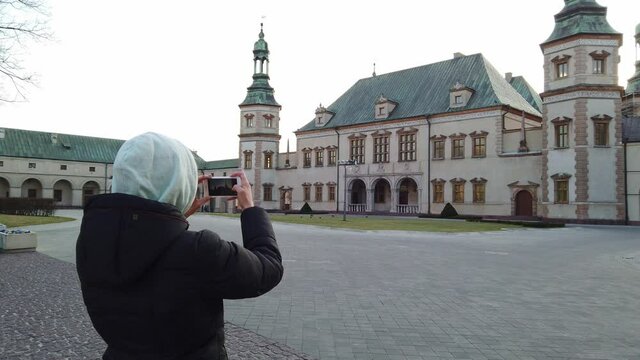 Close-up shot of Girl tourist makes a photos of old palace in the square