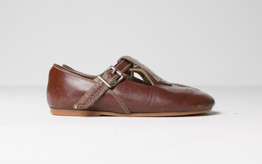 cute little vintage retro brown leather baby dolly shoes, isolated on a white studio background.  Tiny baby sneakers for a baby shower. Babies feet grow fast.