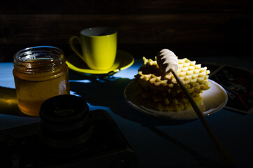 Still life with cup of coffee and waffles on the wooden background. Photo taken in low light key.