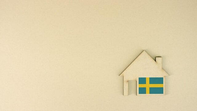 Placing cardboard home icon with printed flag of Sweden. National real estate market concept