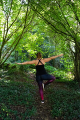 Woman doing yoga in the green forest