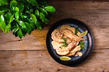 Delicious fried langoustines in sauce on a black plate, prepared in an Asian style. Fast and ready meal concept
