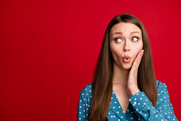 Fototapeta premium Close-up portrait of pretty amazed brown-haired girl looking aside pout lips copy space isolated over bright red color background