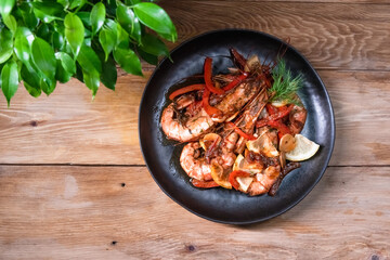 Delicious fried langoustines in sauce on a black plate, prepared in an Asian style. Fast and ready meal concept