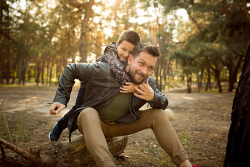 Hugging. Father and son walking and having fun in autumn forest, look happy and sincere. Laughting, playing, having good time together. Concept of family, happiness, holidays, childhood, lifestyle.