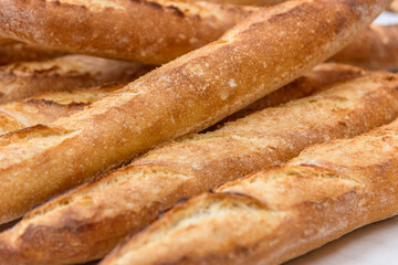 Freshly baked French baguettes lie on a light-colored surface. Rustic handicraft bread, handmade