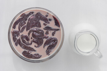 Top view of cut raw pieces of liver in bowl with milk and jar with milk on the white background