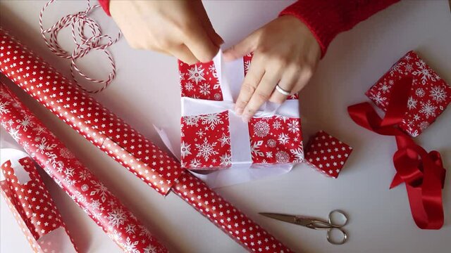 Woman ties a ribbon bow and wrapping presents