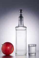 strong alcoholic drink in a beautiful bottle and a faceted glass with a red apple