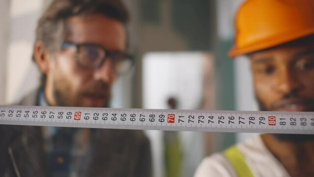 Close up architect and builder using ruler measuring distance in new house