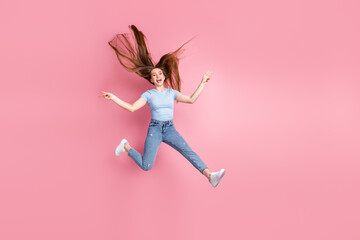 Photo portrait of screaming woman showing two v-signs with fingers jumping up isolated on pastel pink colored background