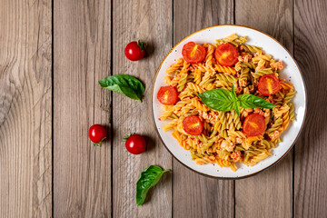 Fusilli - classic italian pasta from durum wheat with chicken meat, tomatoes cherry, basil in tomato sauce in white bowl on wooden table Mediterranean cuisine Top view Flat lay - Powered by Adobe