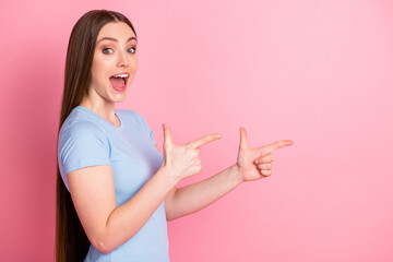 Photo portrait profile of screaming girl pointing two fingers to side isolated on pastel pink colored background