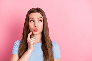 Photo portrait of girl with plump lips touching face chin with finger looking at blank space isolated on pastel pink colored background